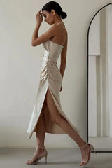 Side view of a woman in a champagne satin slip dress with a cowl neckline and high slit, walking.