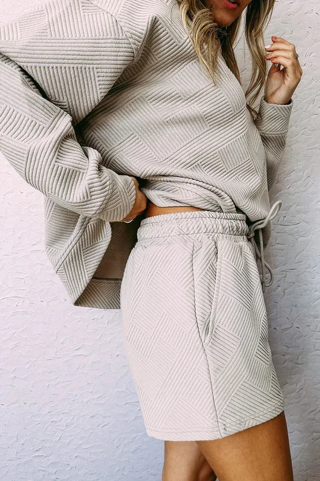 Close-up of a woman's midsection wearing a light beige textured knit top and matching shorts with a drawstring waist.