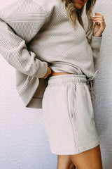 Close-up of a woman's midsection wearing a light beige textured knit top and matching shorts with a drawstring waist.