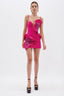 Full-body shot of a model in a bold pink mini dress with statement ruffles and rhinestone accents, paired with platform heels.