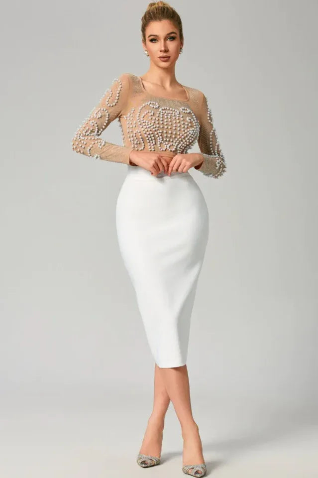 Woman wearing a sheer embellished crop top and white pencil skirt, front view