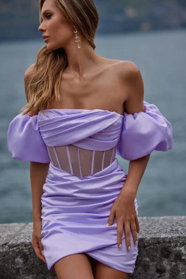 Close-up of a woman in a lavender off-the-shoulder dress with puff sleeves and a sheer corset-style bodice.