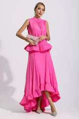Woman in a bright pink two-piece set, holding a light pink clutch.