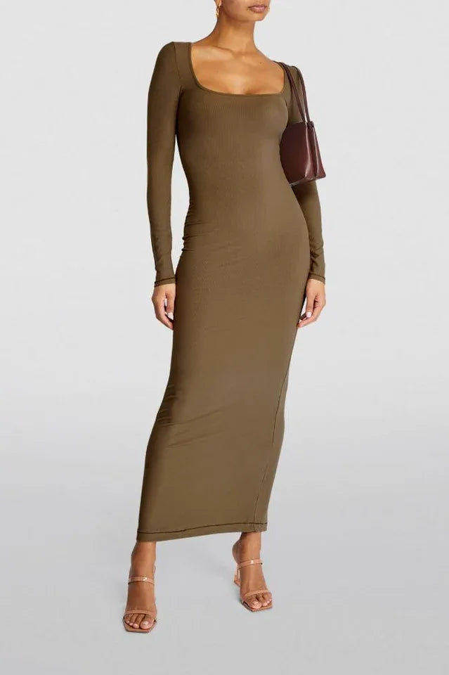 Woman wearing a long-sleeved, ribbed knit, square-neck, olive green maxi dress with heels and a handbag, front view.