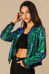 Front view of a woman in a sequined bomber jacket and black jeans, hands in pockets.