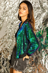 Side view of a woman in a shimmering sequined bomber jacket and black shorts.