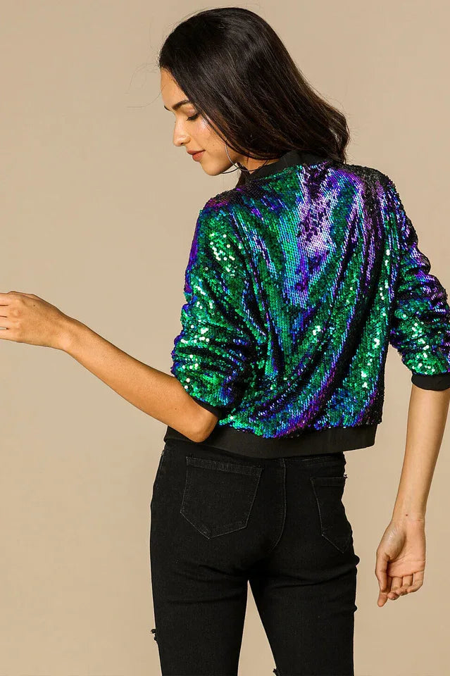 Rear view of a woman wearing a sequined bomber jacket and black jeans.