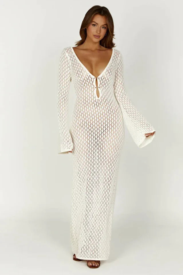 Woman wearing a long white crochet knit dress with bell sleeves and a deep V-neckline, front view