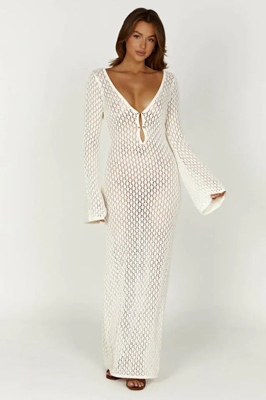 Woman wearing a long white crochet knit dress with bell sleeves and a deep V-neckline, front view