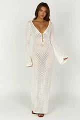 Woman wearing a long white crochet knit dress with bell sleeves and a deep V-neckline, front view