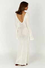 Woman wearing a long white crochet knit dress with bell sleeves and a deep V-neckline, back view