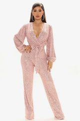 Woman wearing a pink sequined jumpsuit with a V-neck and balloon sleeves