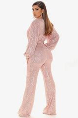Back view of a woman in a pink sequined jumpsuit with a V-neck and balloon sleeves