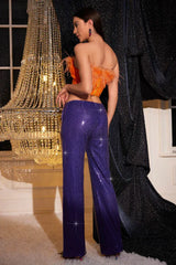 Rear view of the model showcasing the fit of the purple sequin wide-leg pants and the design of the orange top.