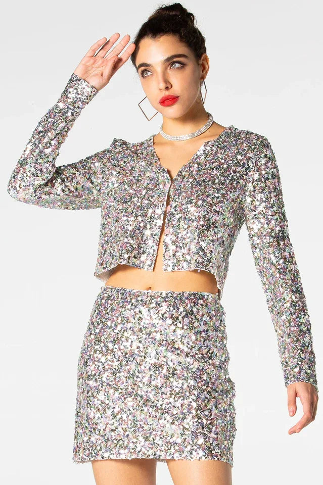 Woman wearing a sequined cropped jacket and matching mini skirt, posing