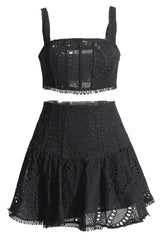 Black embroidered eyelet crop top and flared skirt set laid flat.