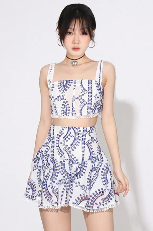 Woman wearing a white and blue embroidered eyelet crop top and flared skirt set.