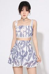 Woman wearing a white and blue embroidered eyelet crop top and flared skirt set.