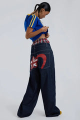Woman wearing dark wash wide leg jeans with plaid waistband detail and a blue t-shirt with yellow stripes