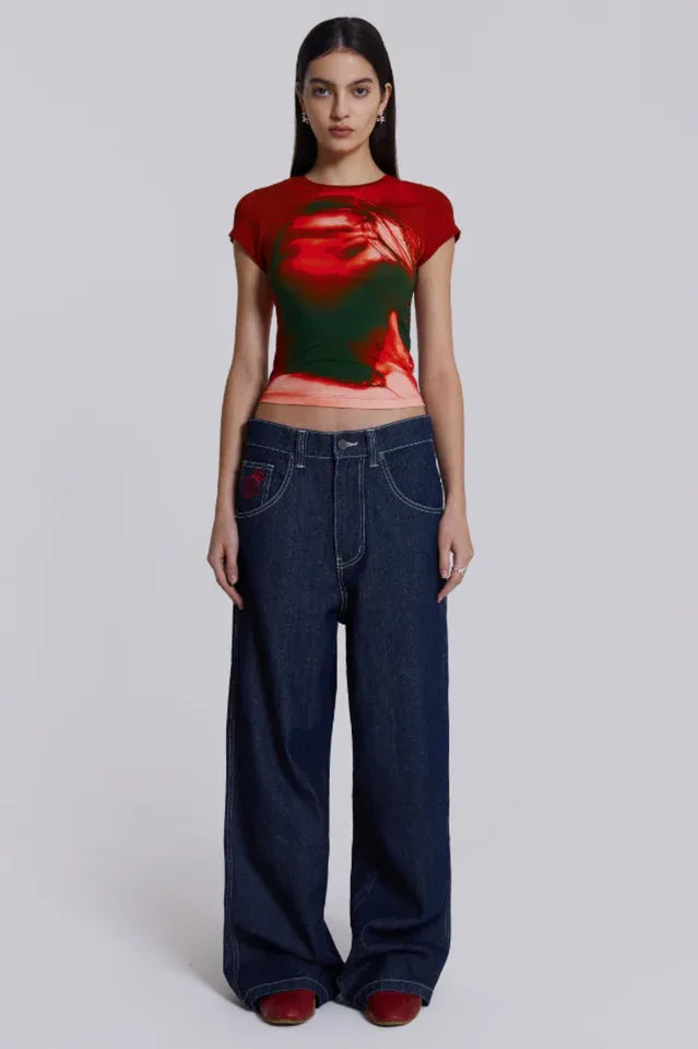 Woman wearing dark wash wide leg jeans and a red and green graphic t-shirt