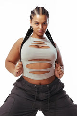 Model with braided hair wearing a light-colored sleeveless cropped top with horizontal cut-outs, paired with dark cargo pants.