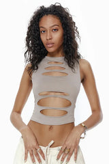 Model wearing a taupe sleeveless cropped top with horizontal cut-outs on the front, paired with light-colored cargo pants.