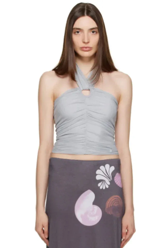 woman wearing a light blue ruched halter top and grey skirt on a white background
