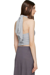 woman from behind wearing a light blue ruched halter top and grey skirt on a white background
