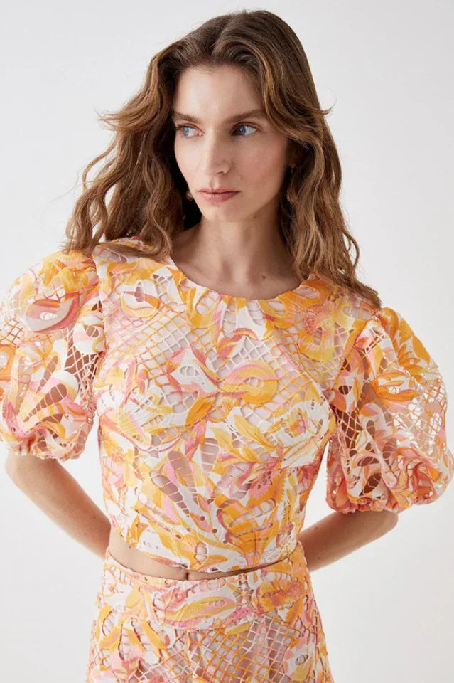 Close-up of the cropped top, showcasing the round neckline, puff sleeves, and intricate floral lace pattern.