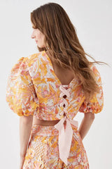 Back view of the cropped top, highlighting the lace-up detail with pink ribbon.