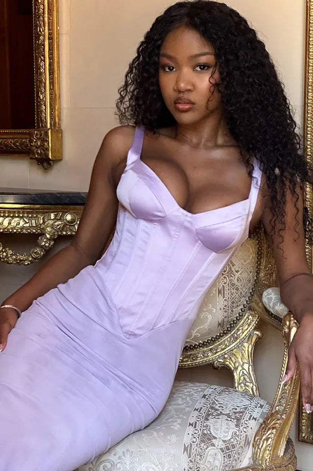 Close-up of a woman wearing a lavender corset dress while seated on an ornate chair.