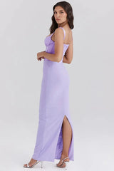 Rear side view of a woman wearing a long lavender corset dress with a slit hem.
