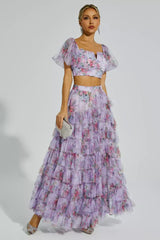 Woman wearing a floral print two-piece set with a crop top and tiered maxi skirt.