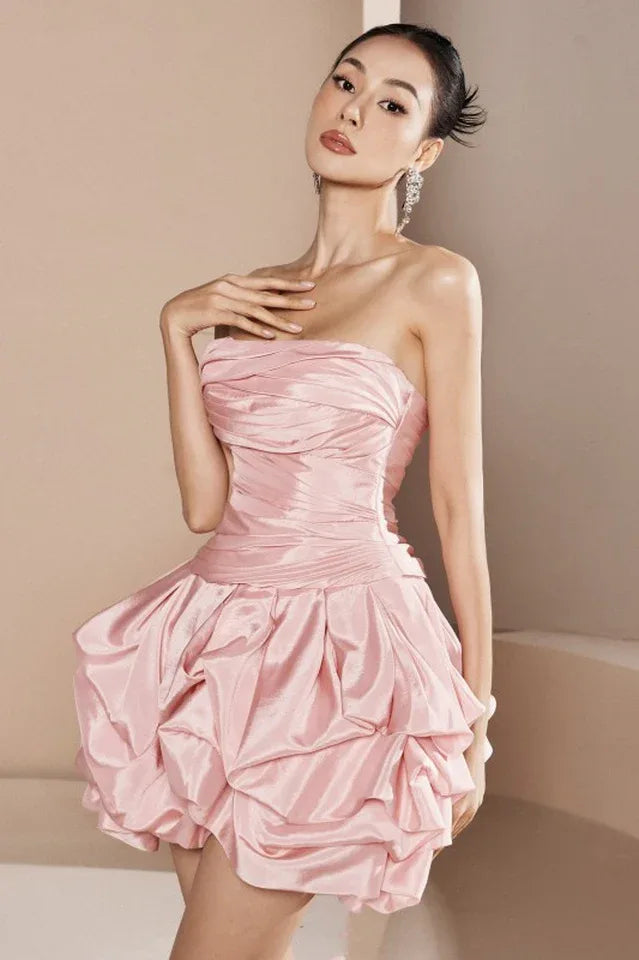 woman wearing a pink strapless ruched mini dress with a tiered ruffle bubble hem skirt