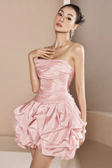 woman wearing a pink strapless ruched mini dress with a tiered ruffle bubble hem skirt