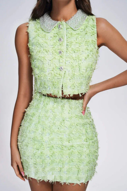 Close-up of a lime green textured tweed crop top and mini skirt set with embellished collar.