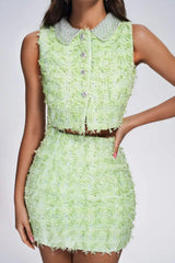 Close-up of a lime green textured tweed crop top and mini skirt set with embellished collar.