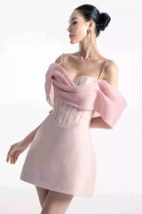 Woman wearing a pink off-the-shoulder mini dress with a textured bodice and chiffon overlay