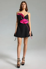 Full length view of a black mini dress with pink floral applique, spaghetti straps, and flared skirt