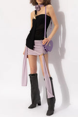 Model wearing a black one-shoulder draped top with a lavender skirt and boots