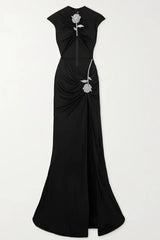 Full view of a black velvet evening gown with a cut-out, high slit, and rose embellishment.