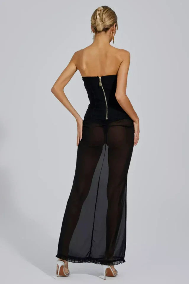 Rear view of a woman in a strapless corset dress with a sheer black maxi skirt, showing a back zipper.