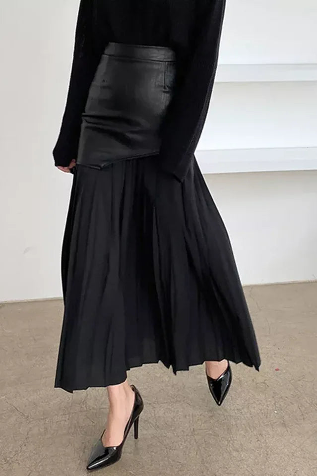 Close-up of a black paneled pleated skirt with black sweater and black heels