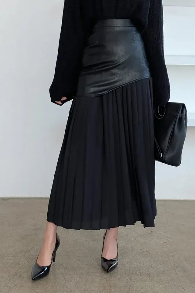 Model wearing a black paneled pleated skirt with black sweater and black heels