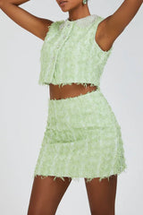 Full body shot of a model in a lime green textured tweed crop top and mini skirt set with embellished collar.