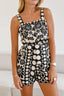 Woman wearing a black and white floral print romper with a square neckline and shorts.