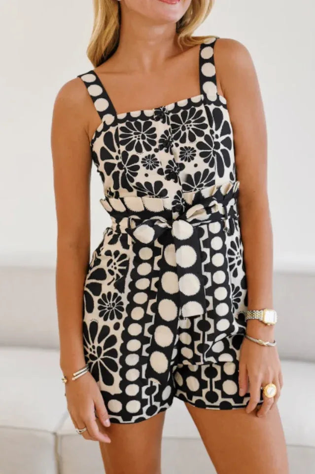 Woman wearing a black and white floral print romper with a square neckline and shorts.