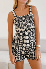 Woman wearing a black and white floral print romper with a square neckline and shorts.