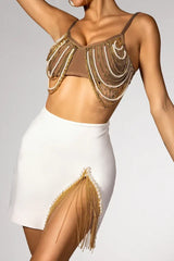 Woman posing in a stylish brown chain-and-bead embellished bralette top and a white high-slit skirt with fringe.