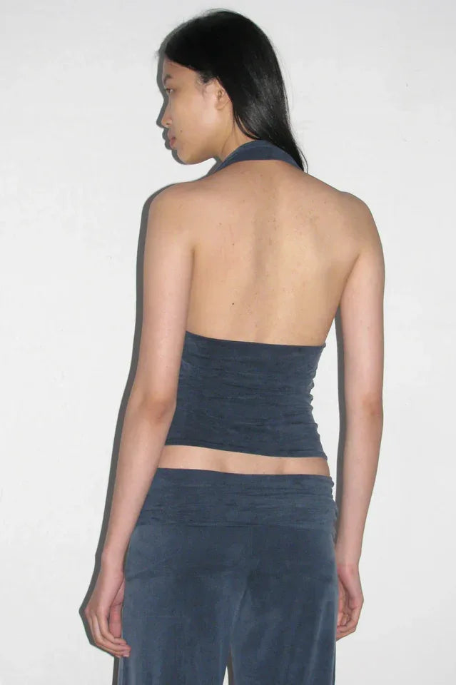 Back view of a woman wearing a dark blue halter neck crop top and dark blue wide leg pants.